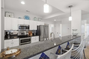 A modern kitchen with white cabinets, stainless steel appliances, a granite countertop, and a central island with bar stools. - Main Channel Views, 3 Heated Pools & Gated Resort (Lake Ozark)
