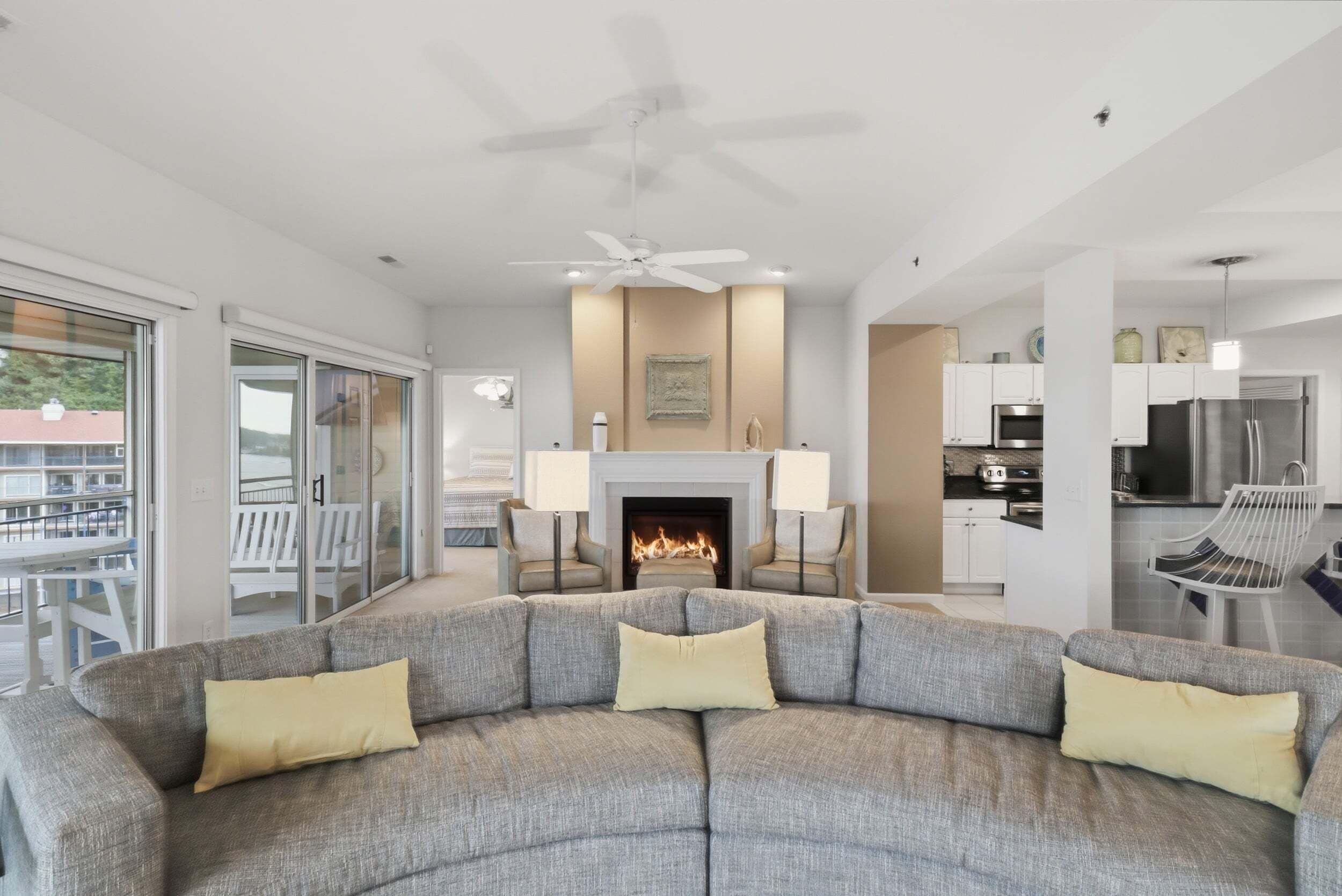 A modern living room with a sectional sofa, a fireplace, and a kitchen area.
