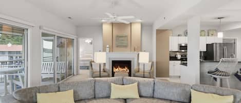 A modern living room with a sectional sofa, a fireplace, and a kitchen area.