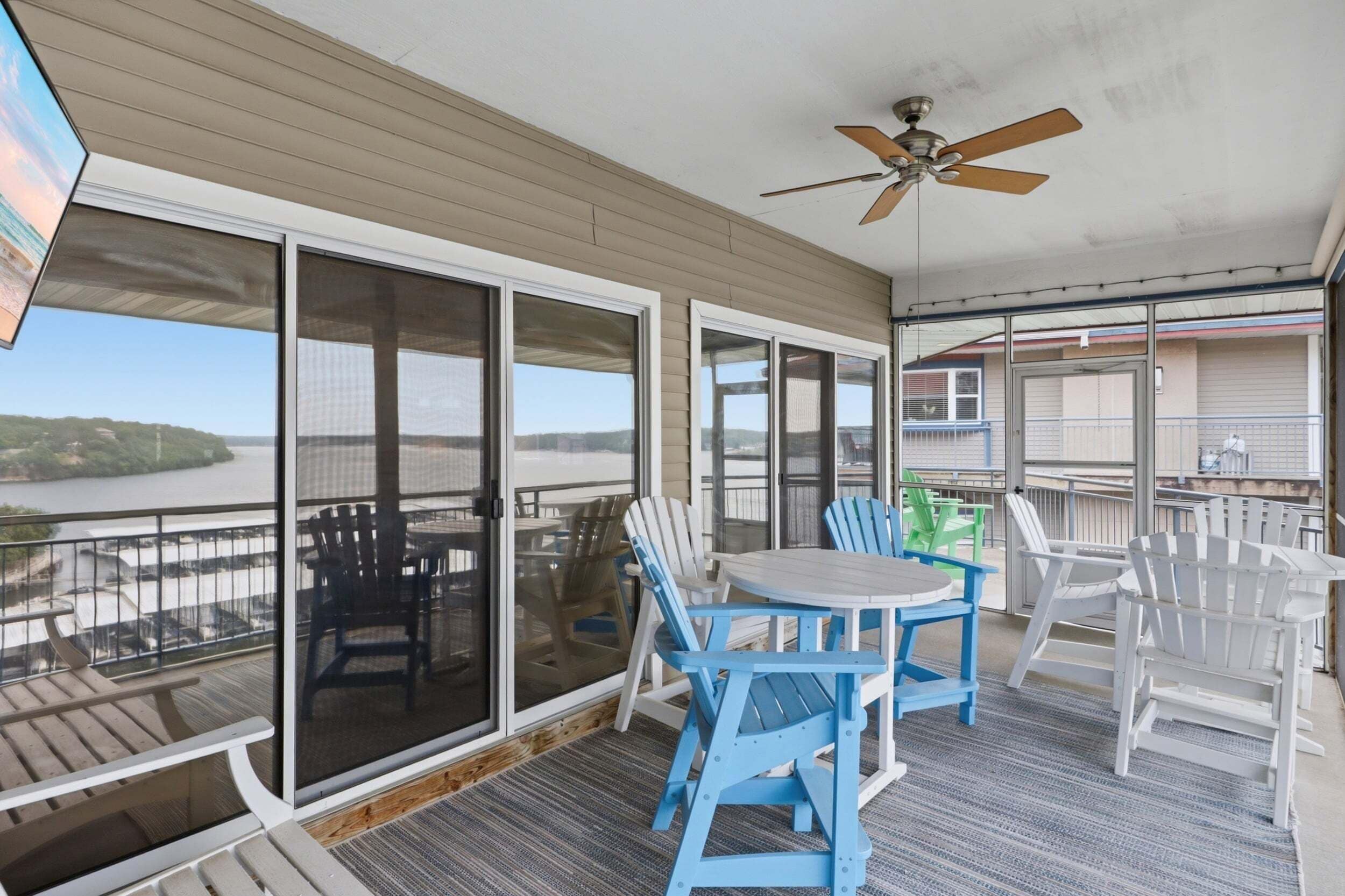 A covered outdoor area with a table and chairs, a ceiling fan, and a view of a body of water.