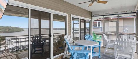 A covered outdoor area with a table and chairs, a ceiling fan, and a view of a body of water.