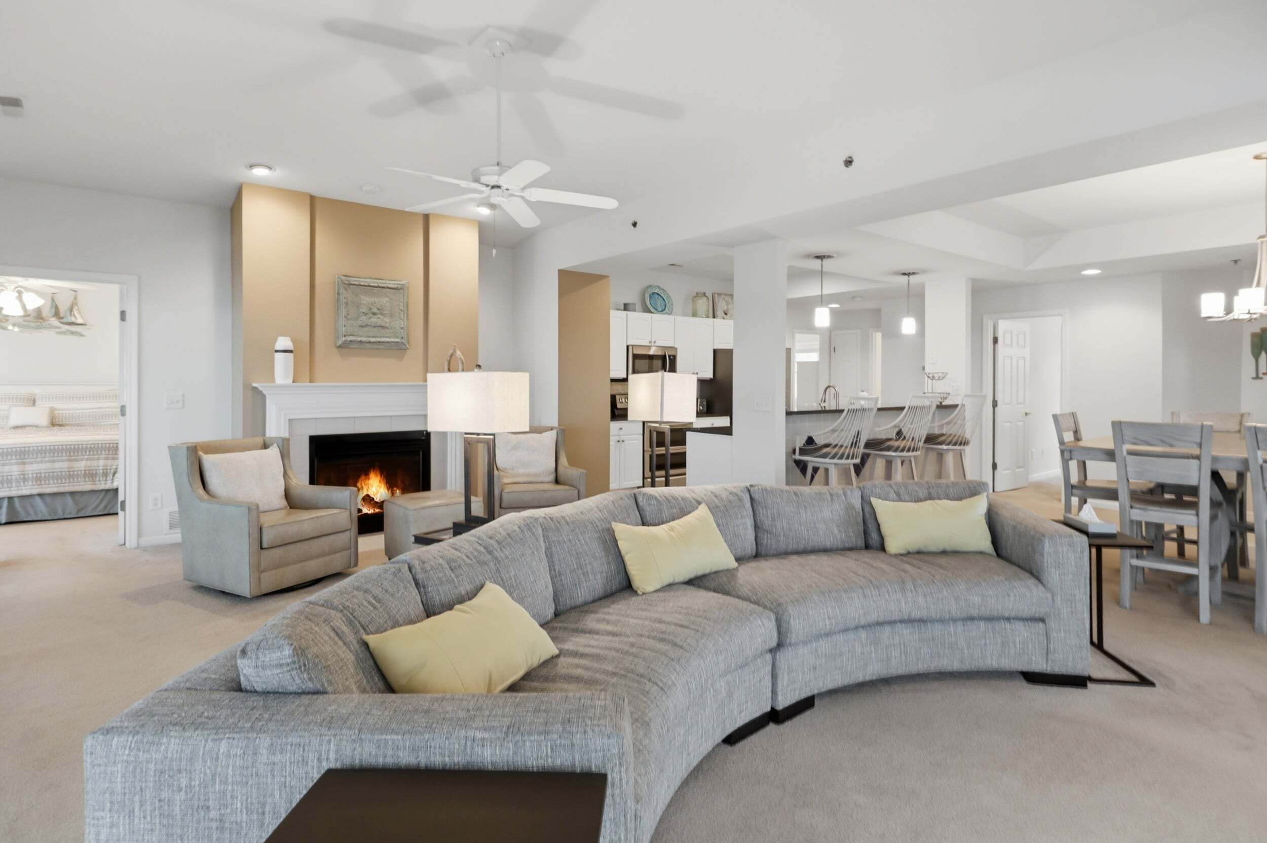 A modern living room with a large sectional sofa, a fireplace, and a dining area with a chandelier.