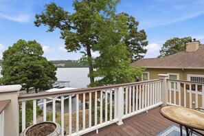 A deck with a railing, a table, and a view of a lake and trees. - Executive Style Lakefront Porto Cima Retreat (Sunrise Beach)