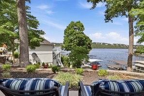 Una propiedad frente al lago con una terraza, mobiliario exterior y vistas al agua.