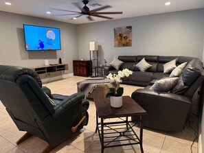 A living room with a TV, leather sofas, a coffee table, and a ceiling fan. - Welcome to your Private Lake Worth Oasis getaway! (Lake Worth)