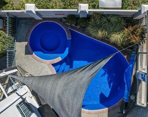 Ein Pool auf dem Dach mit einer runden Rutsche und einem schattigen Bereich.