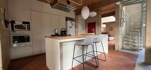 A modern kitchen with a central island, bar stools, built-in ovens, and a visible staircase. - Architectural Gem in Geelong (Greater Geelong)