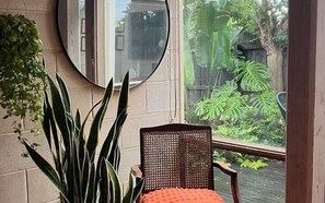 A room with a chair, a potted plant, and a view of greenery outside. - Architectural Gem in Geelong (Greater Geelong)
