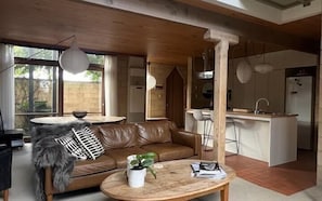 A modern living room with a leather sofa, a round wooden coffee table, and a dining area with a white table and chairs. - Architectural Gem in Geelong (Greater Geelong)