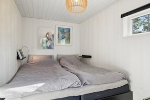 A bedroom with a bed, two wall-mounted nightstands, a ceiling light fixture, and two framed artworks. - Cozy holiday home with hot tub (Løgstør)