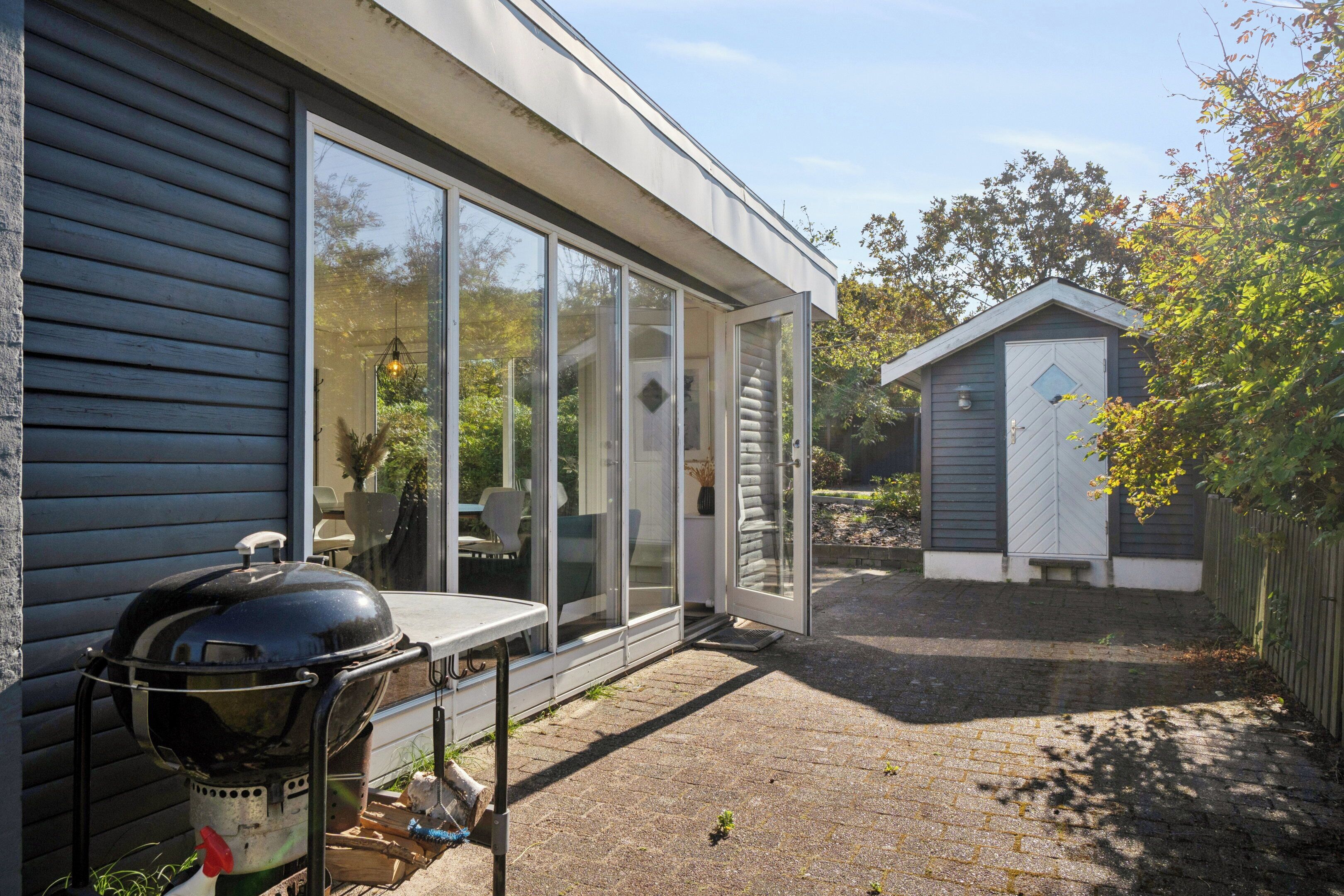 Ein modernes Haus mit einer großen Schiebeglastür, die auf eine Terrasse führt.