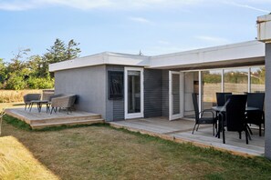 A modern house with a patio area, outdoor seating, and a sliding glass door leading to a covered outdoor space. - Cozy holiday home with hot tub (Løgstør)