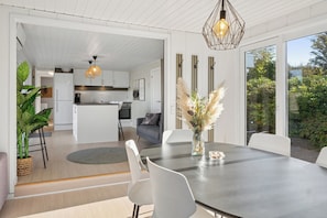 A modern kitchen with white cabinets, a central island, and pendant lighting. - Cozy holiday home with hot tub (Løgstør)