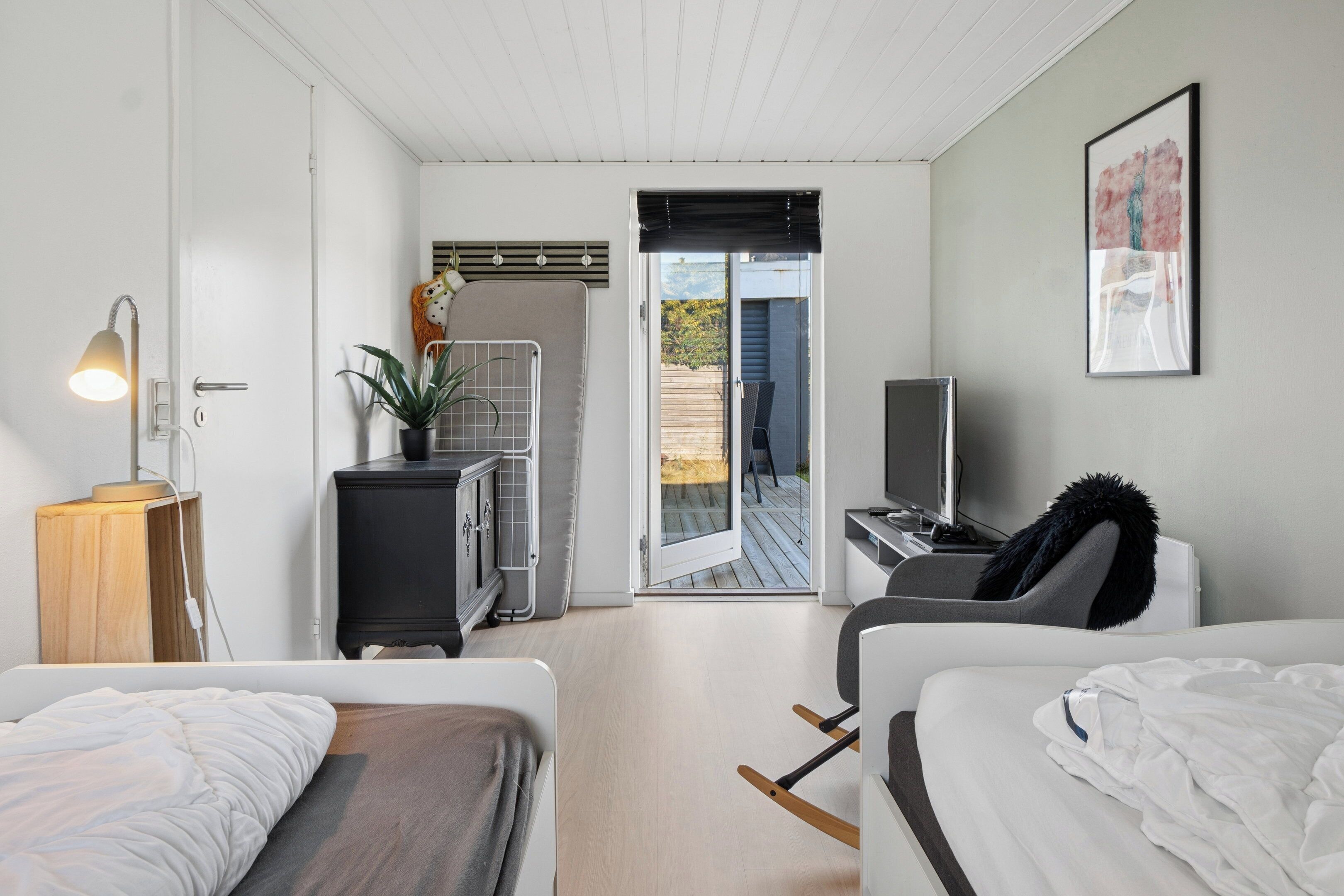 Een moderne slaapkamer met een bed, nachtkastje, lamp en een televisie.