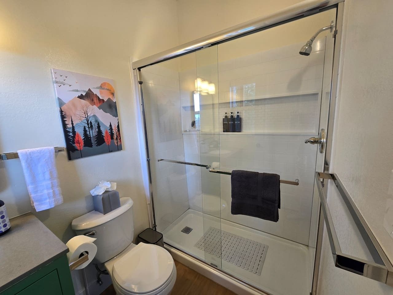 A bathroom with a glass-enclosed shower, a toilet, and a sink.