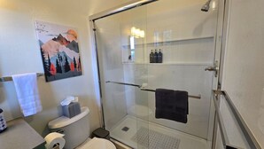 Een badkamer met een douchecabine, toilet en wastafel.