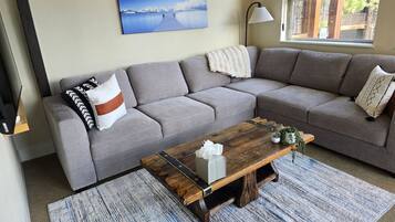 A living room with a grey sofa, a wooden coffee table, and a painting of a landscape on the wall.