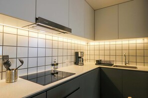 A modern kitchen with a black stove, white tiles, and a coffee maker. - w* | Amazing 2BR with Balcony in Prime Miraflores (Miraflores)