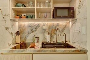 A kitchen with a marble backsplash, a sink, a microwave, and various kitchen utensils. - w* | Enchanting 1BR in the Heart of Zona T (Bogotá)