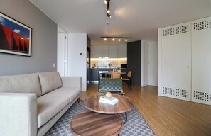 A modern living room with a sofa, two wooden coffee tables, and a dining area with a table and chairs. - w* | Upscale 2BR with Balcony in Prime Miraflores (Miraflores)