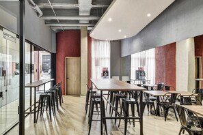 A modern conference room with long tables and chairs, large windows, and a red accent wall. - w* | Refined Loft w/ Balcony in Usaquen (Bogotá)
