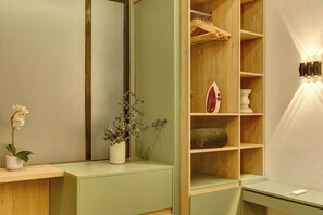 Ein Zimmer mit einem Holzschrank, einem Spiegel, einem kleinen Tisch mit einer Pflanze und einer Wandleuchte.