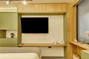 A bedroom with a bed, a TV mounted on the wall, a small shelf with a plant, and a bedside table with an hourglass and a lamp. - w* | Charming & Cozy 3BR in the Heart of Zona T (Bogotá)