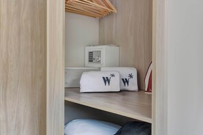 Quarto compacto com uma cama, uma mesinha de cabeceira, um armário branco e um aquecedor.