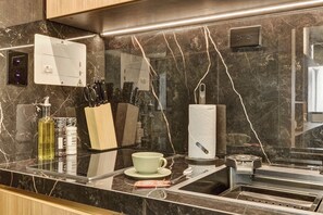 A kitchen with a marble countertop, a coffee maker, a knife block, and a paper towel dispenser. - w* | Charming 1BR in the Heart of Zona T (Bogotá)