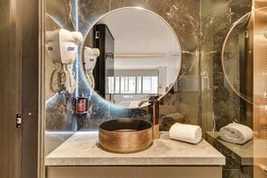 A bathroom with a round mirror, a sink with a copper basin, and a towel on the counter. - w* | Charming 1BR in the Heart of Zona T (Bogotá)