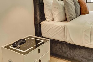 A neatly made bed with a dark headboard, a bedside table with a charging station, and a small drawer unit. - w* | Charming 1BR in the Heart of Zona T (Bogotá)
