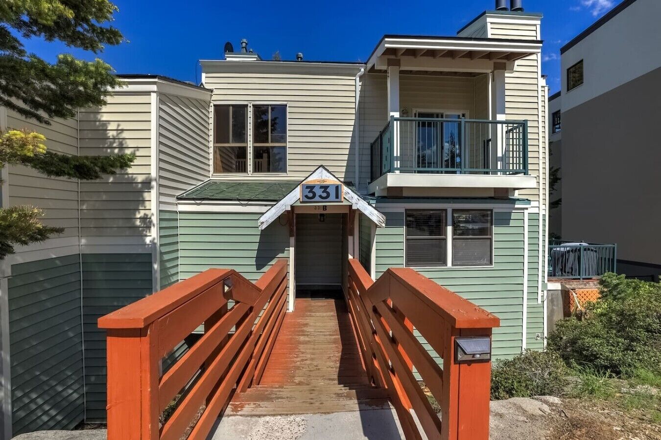 A two-story building with a balcony and a wooden bridge leading to the entrance.
