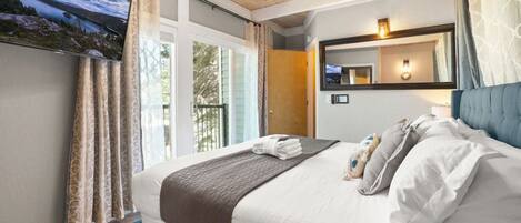 Una habitación de hotel con una cama, un televisor montado en la pared y una ventana con cortinas.