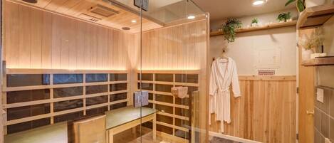 Un sauna moderno con paneles de madera, paredes de vidrio y un banco.
