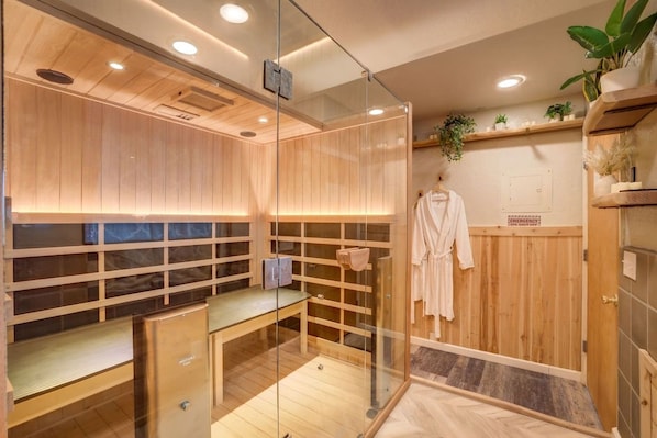 A modern sauna room with wooden paneling, glass walls, and a bench.