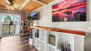 Ein modernes Wohnzimmer mit Holzboden, einem großen Fernseher, einem Gemälde und einer Bar mit Regalen.