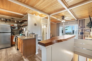 A modern kitchen with a central island, wooden ceiling, and built-in appliances.