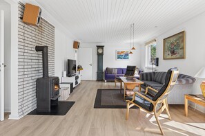 A modern living room with a fireplace, a sofa, a television, and a painting on the wall. - Holiday home near central Gedser (Gedser)