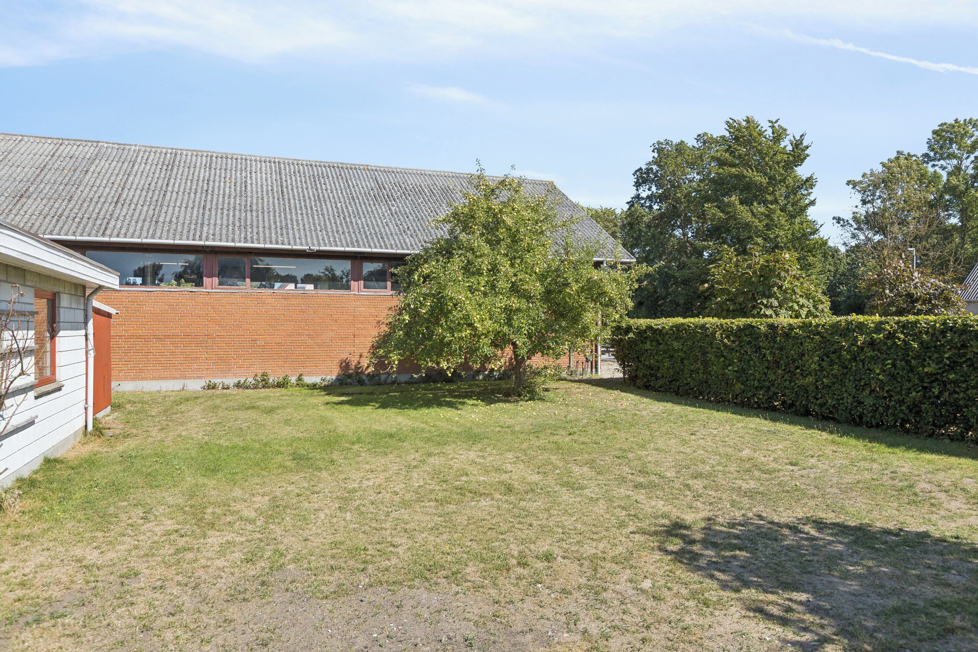 A residential property with a brick building, a grassy yard, and a tree.