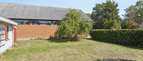 A residential property with a brick building, a grassy yard, and a tree.