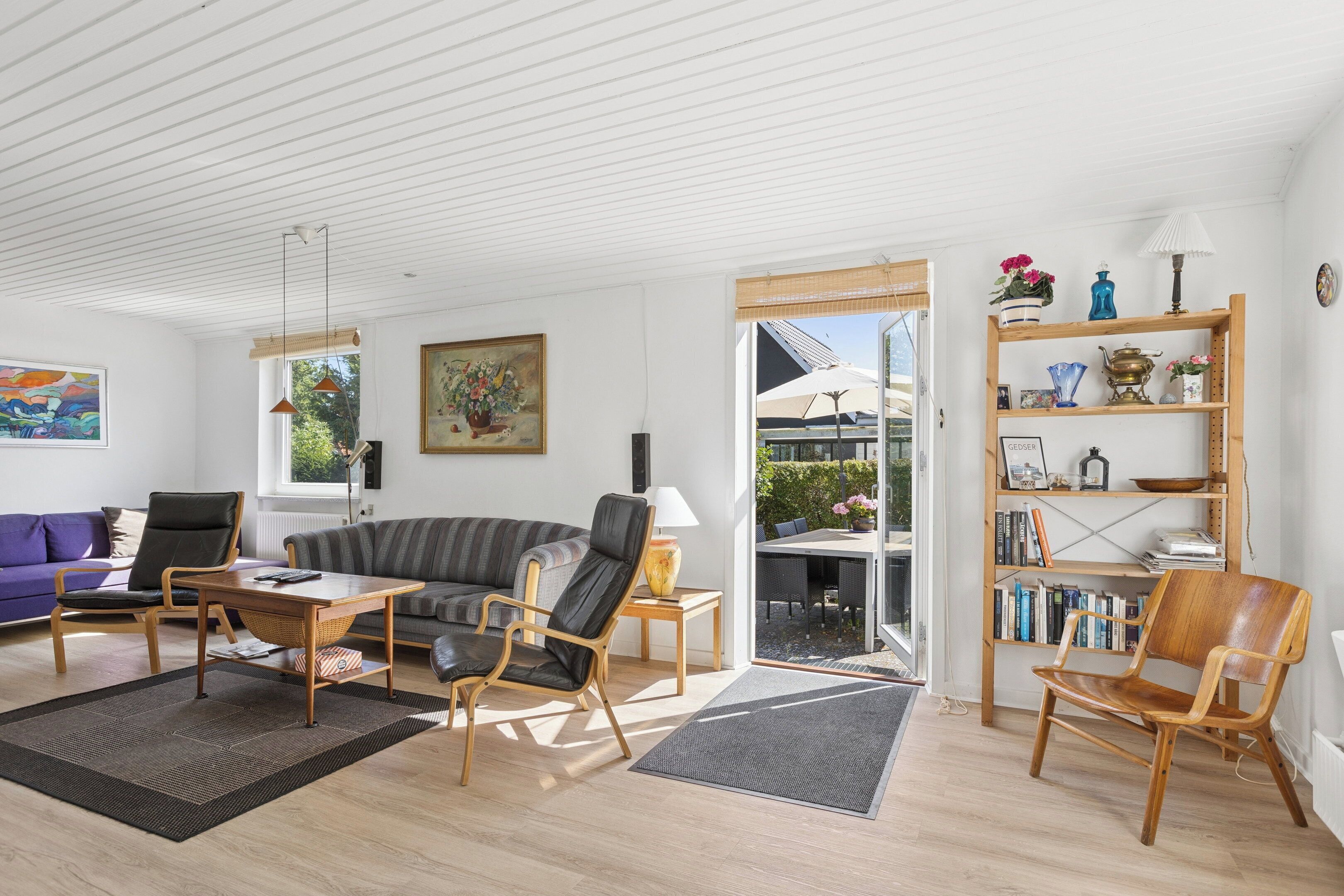 A modern living room with a sofa, chairs, a coffee table, a bookshelf, and a painting.