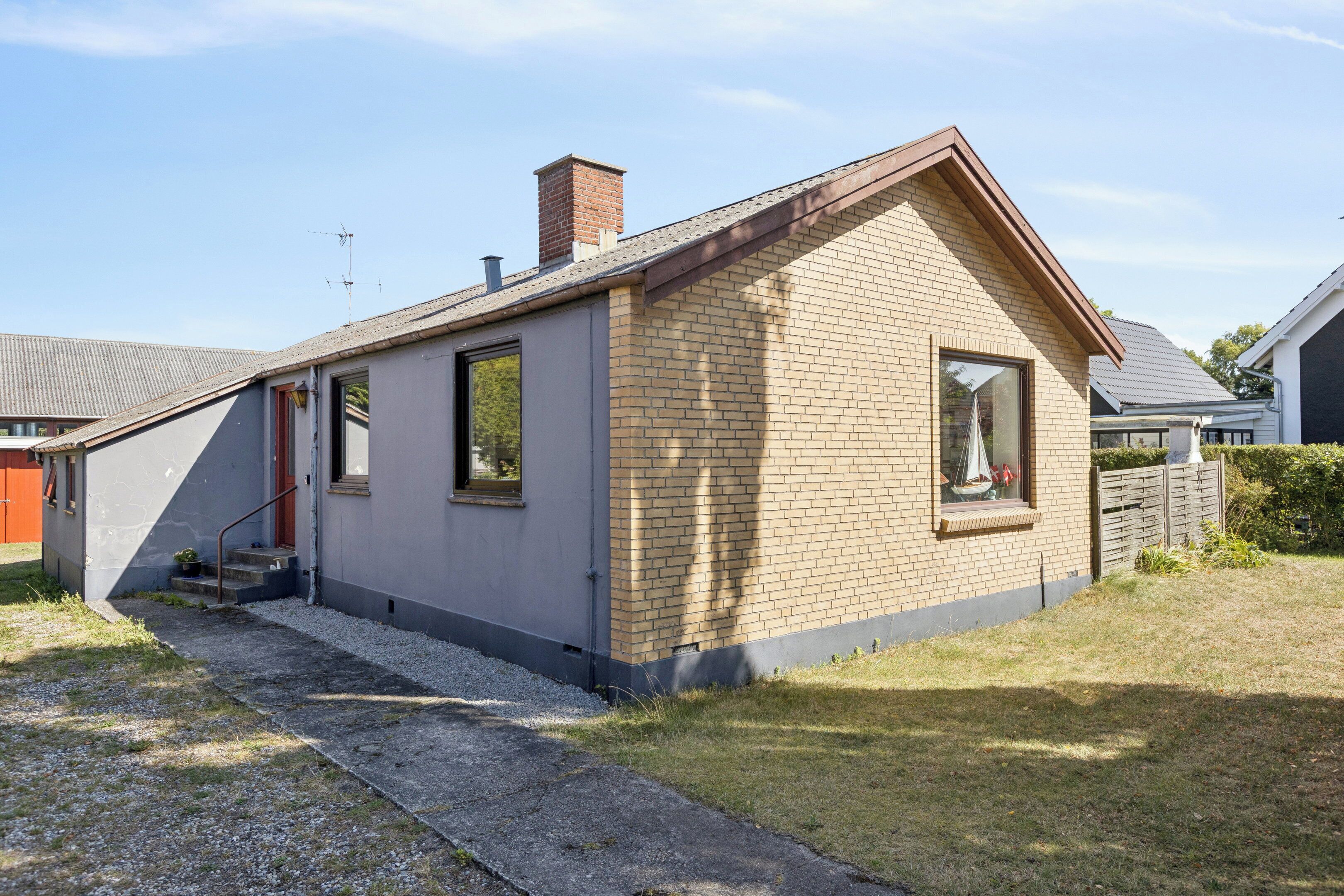A small, single-story house with a sloped roof, a chimney, and a front door.