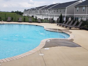 A swimming pool with a curved edge, surrounded by lounge chairs and a paved deck. - Charming bedroom in fantastic Spartanburg with cool AC (Spartanburg)
