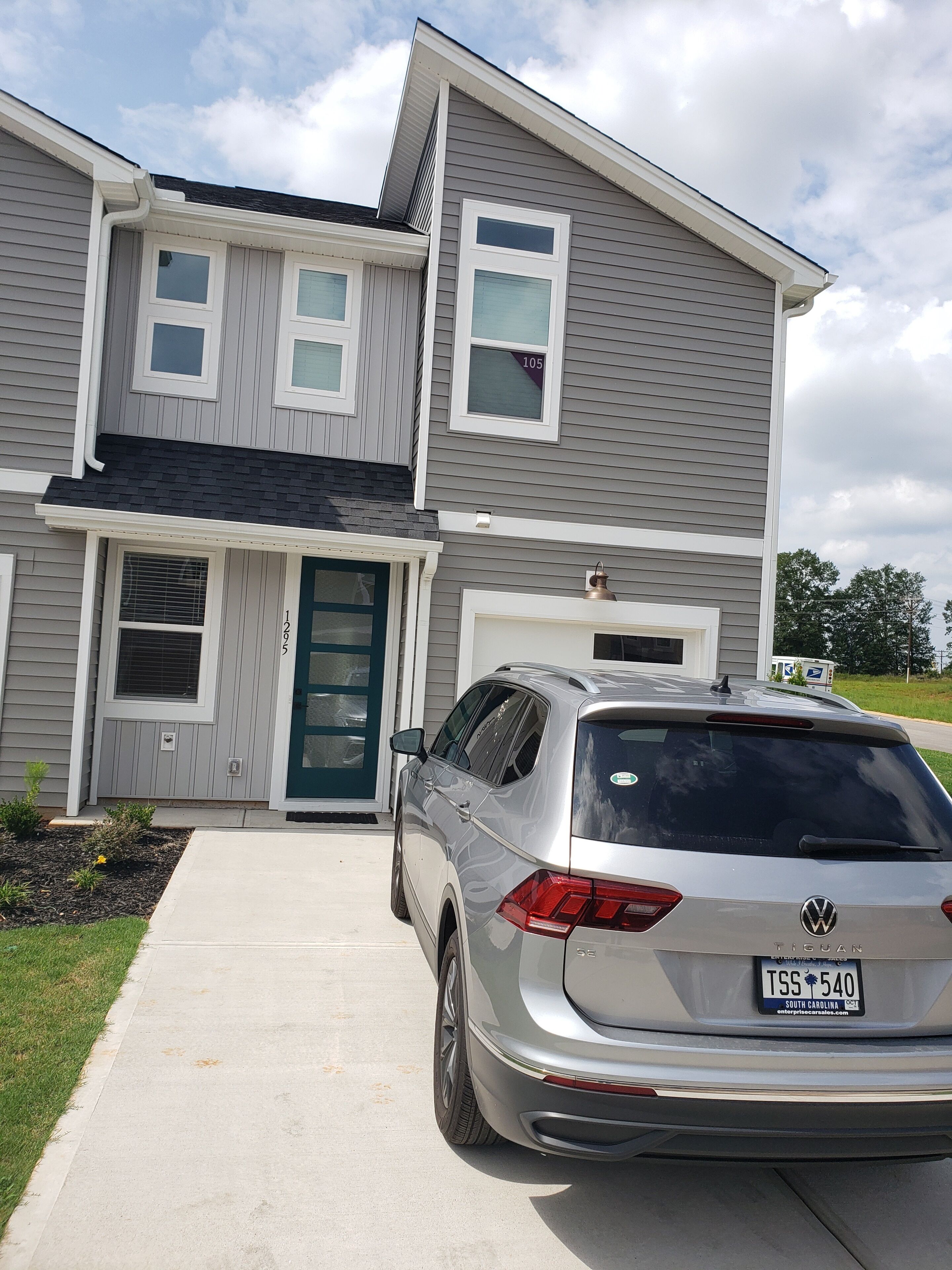 A two-story house with a grey exterior and a silver SUV parked in front.