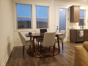 A dining area with a table, chairs, and a laptop. There is a kitchen area with cabinets and a sink. - Charming bedroom in fantastic Spartanburg with cool AC (Spartanburg)