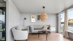 Un salon moderne avec deux canapés, une table basse ronde et un luminaire suspendu en rotin.