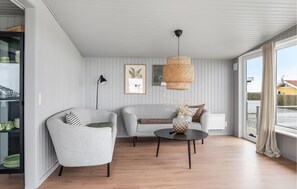 A modern living room with two sofas, a round coffee table, and a hanging rattan light fixture. - 3 bedroom awesome home in Lemvig (Lemvig)