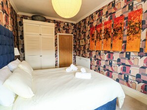 A hotel room with a large bed, a wardrobe, and a patterned wall. - FLAT 3, family friendly, country holiday cottage in Llandudno (Llandudno)