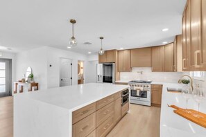 A modern kitchen with a large island, wooden cabinets, and stainless steel appliances. - LUX 6BR 3 Suites 3 Kitchens Pool 2 Huge Backyard Firepit (Las Vegas)
