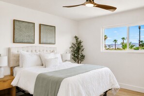 A bedroom with a bed, two wall-mounted artworks, a window with a view, and a ceiling fan. - LUX 6BR 3 Suites 3 Kitchens Pool 2 Huge Backyard Firepit (Las Vegas)